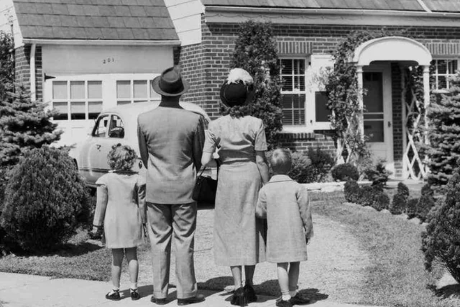 1950s american family standing in front of a house
