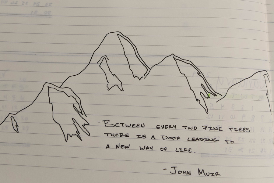 A simple hand-drawn sketch of a mountain range on lined notebook paper, accompanied by a handwritten quote that reads: "Between every two pine trees there is a door leading to a new way of life. – John Muir." A small patch of green is added to one tree on the right.